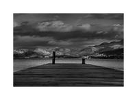 Black and white photograph of a lake with a pier in the foreground